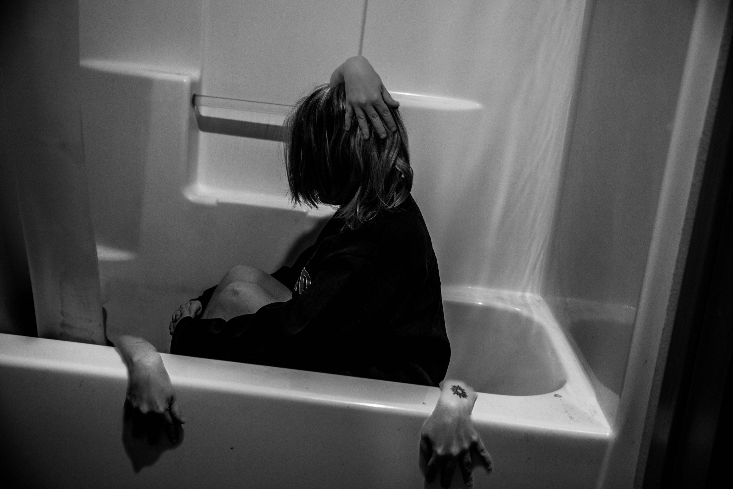 Girl sits in tube with hands coming out of the tub that aren't hers. And there's a hand coming out of her head.