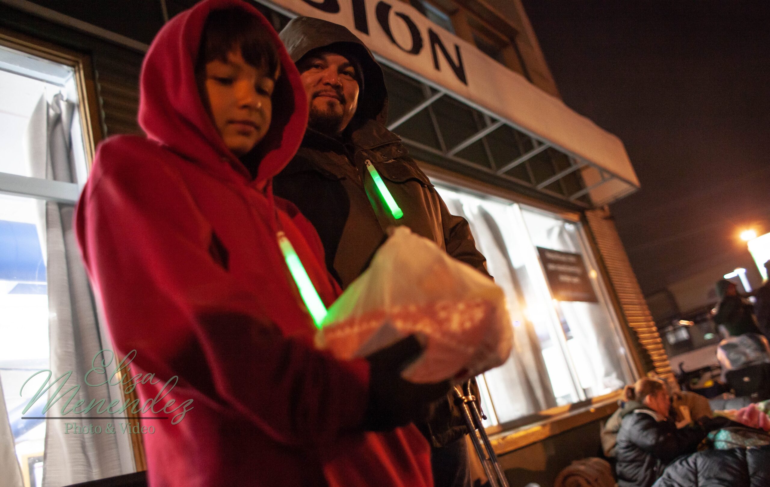 A kid holds out a bag with food in it next to his dad at the Kitsap Rescue Mission.